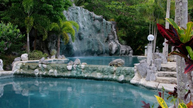 A pool with a waterfall, surrounded by rocks and tropical plants. - Momarco Forest Cove Resort And Hotel (Tanay)