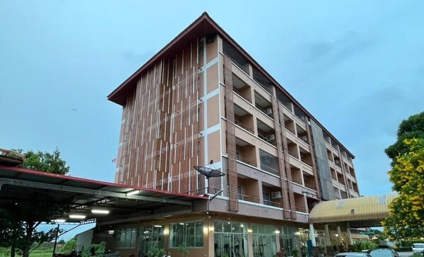 A multi-story building with a flat roof and a covered entrance area.