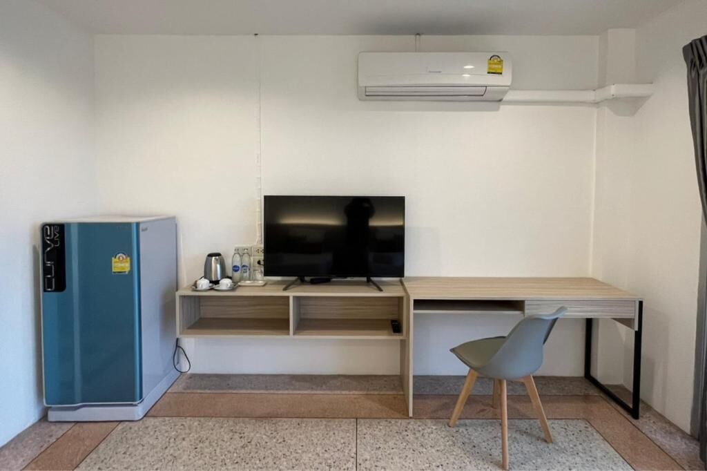 Habitación compacta con kitchenette, televisión de pantalla plana, escritorio y silla.