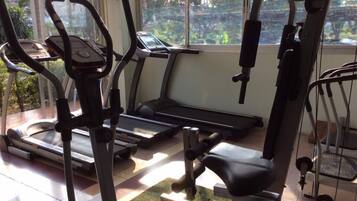 Ett gym med löpband, en motionscykel och utrustning för styrketräning.