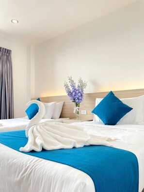 A hotel room with a large bed, a vase of flowers, and a blue and white color scheme. - AK Terrace (Nong Khae)