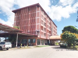 Un edificio de varios pisos con fachada roja y un área de entrada cubierta.