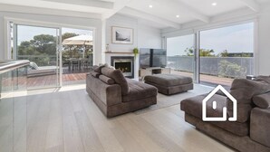 Amplia sala de estar con chimenea, televisor y balcón con vistas.