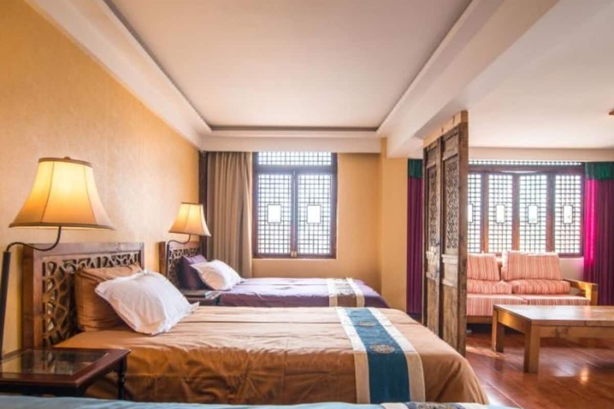 A hotel room with two beds, a sofa, and a table.