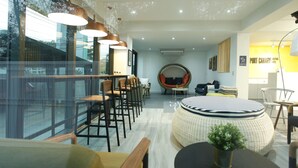 A modern hotel lobby with a seating area, a round wicker sofa, and a dining table. - Port Canary Hotel (Bangkok)
