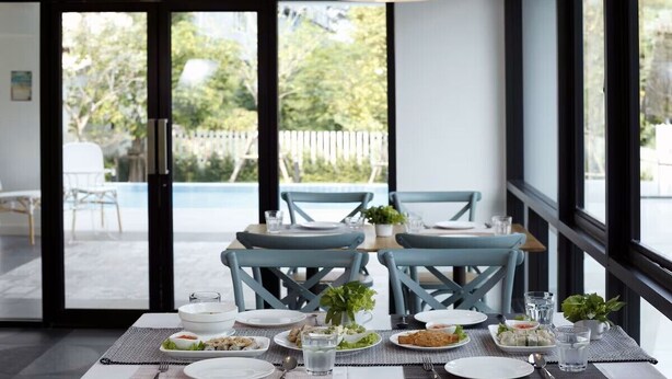 A dining area with a table set for four, chairs, and a view of the outdoors. - Port Canary Hotel (Bangkok)