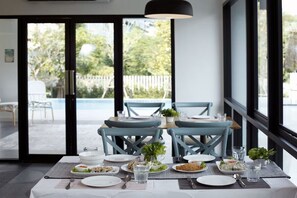 A dining area with a table set for four, chairs, and a view of the outdoors. - Port Canary Hotel (Bangkok)