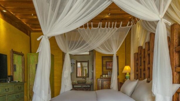 A wooden four-poster bed with white bedding and a canopy. - Floral Hotel Sen Du Lijiang (Lijiang)