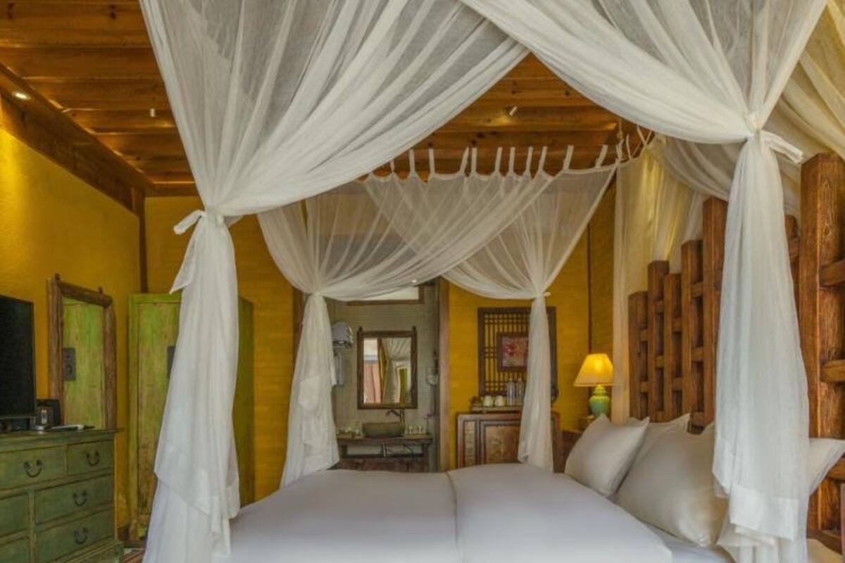 A wooden four-poster bed with white bedding and a canopy.