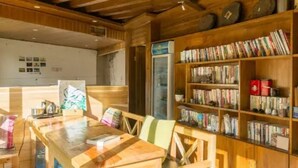 A wooden interior with a dining table and chairs, a bookshelf filled with books, and a refrigerator. - Floral Hotel Sen Du Lijiang (Lijiang)