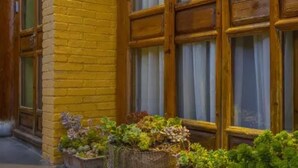 A yellow brick building with large wooden windows and potted plants in front. - Floral Hotel Sen Du Lijiang (Lijiang)