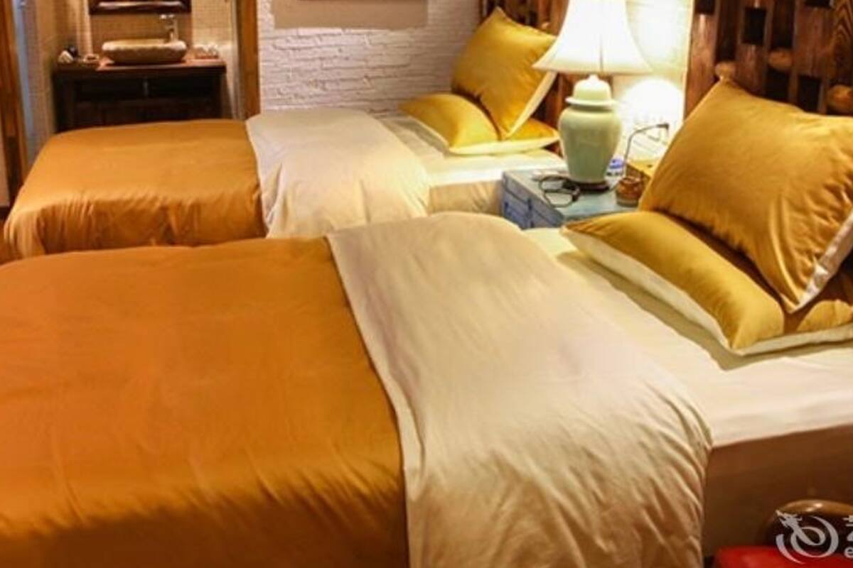 A hotel room with two beds, a nightstand, a lamp, and a mirror.