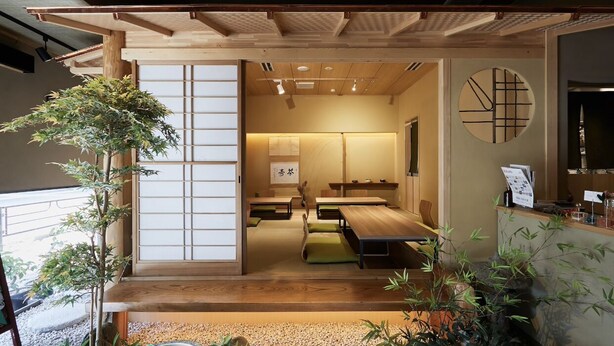 Une pièce de style japonais traditionnel, avec un sol recouvert de tatamis, une petite table en bois et une porte coulissante.