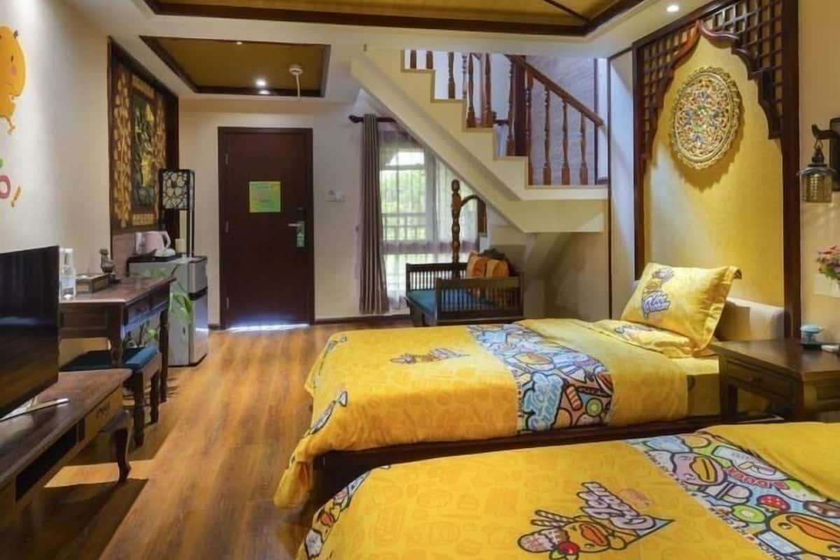 Une chambre d’hôtel avec deux lits, un plafond en bois, un escalier et un mur décoratif.