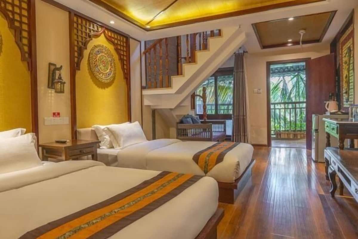 Une chambre d’hôtel avec deux lits, un escalier et une vue sur la verdure environnante.
