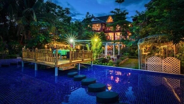 A large, multi-story hotel with a swimming pool, surrounded by lush greenery.