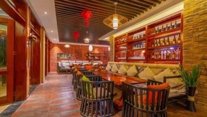 A bar area with wooden shelves, a sofa, and a dining table with chairs.