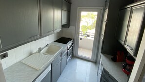 A modern kitchen with grey cabinets, a double sink, and a built-in oven. - One Bedroom - Rue D'Antibes (Cannes)