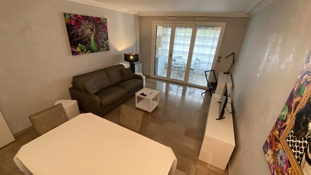 A modern living room with a sofa, a dining table, and a large window. - One Bedroom - Rue D'Antibes (Cannes)