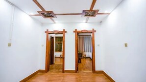 A hallway with wooden flooring and white walls, leading to two rooms with wooden doors and a ceiling with a geometric design. - Floral Hotel · Spring Guesthouse Zhangjiajie (Zhangjiajie)