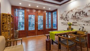 A traditional-style room with wooden furniture, a dining table with a green tablecloth, and a large mural on the wall. - Floral Hotel · Spring Guesthouse Zhangjiajie (Zhangjiajie)