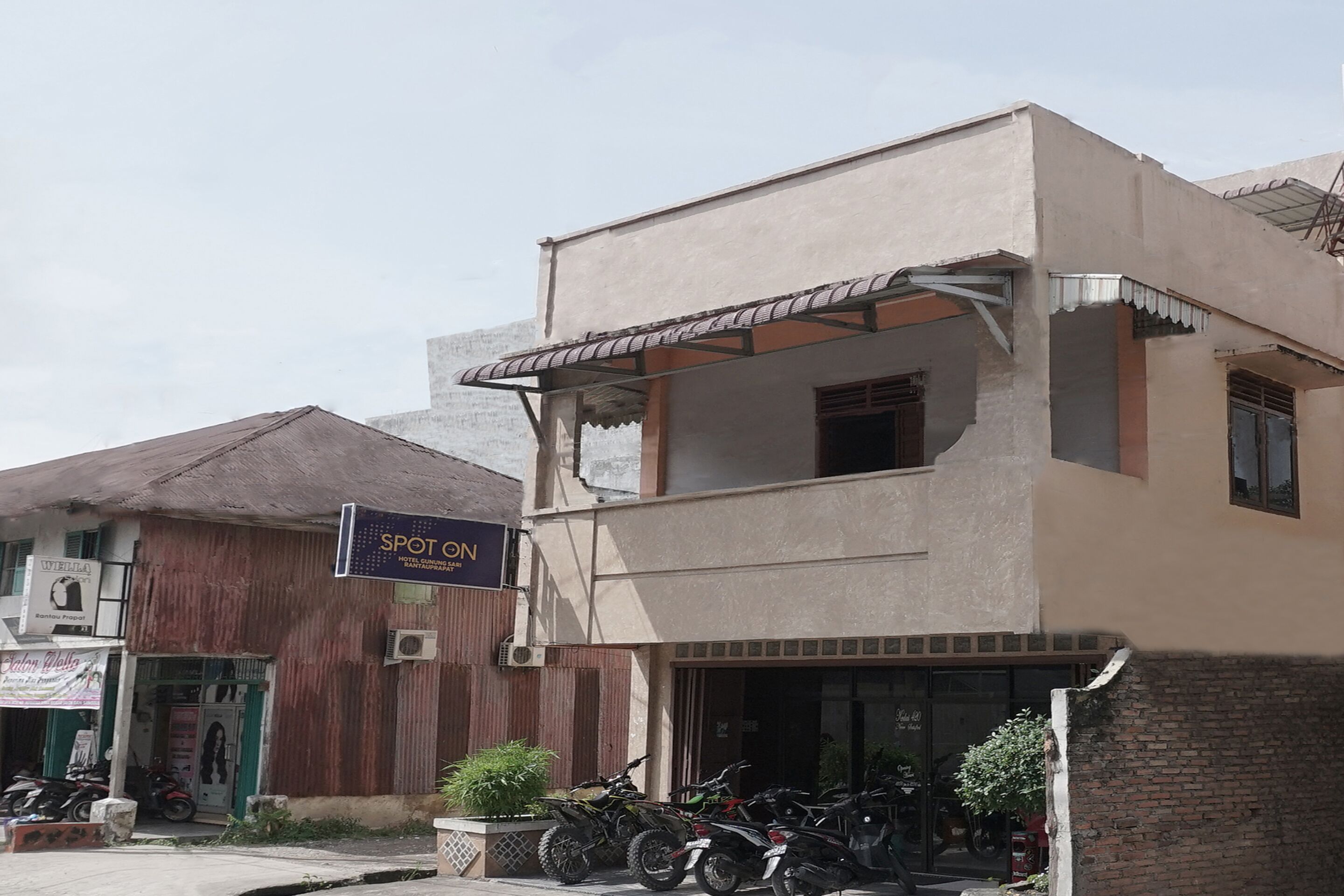 A two-story building with a sign for "Spot On" and a motorcycle parked in front.