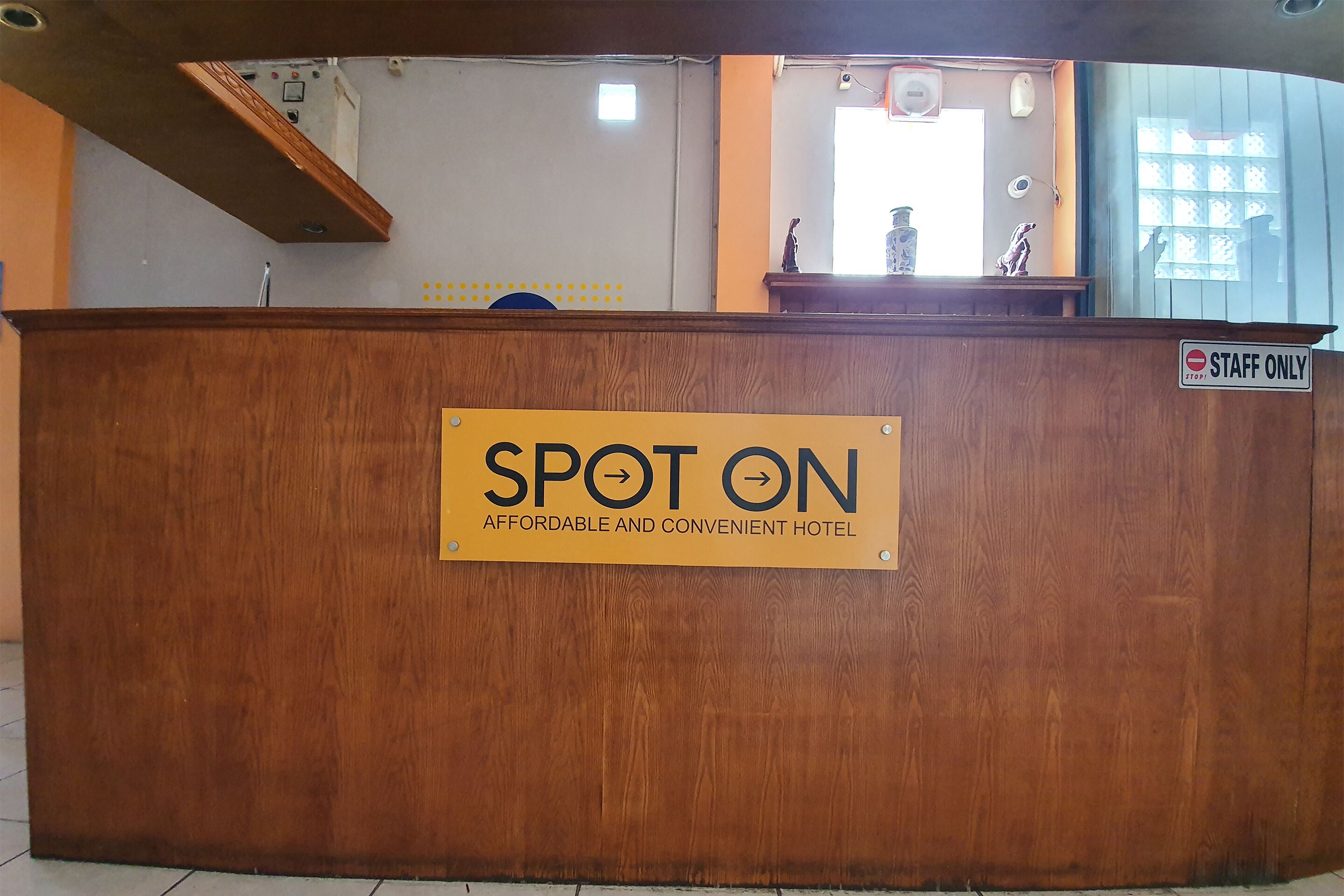 A wooden reception desk with a sign reading "SPOT ON AFFORDABLE AND CONVENIENT HOTEL."