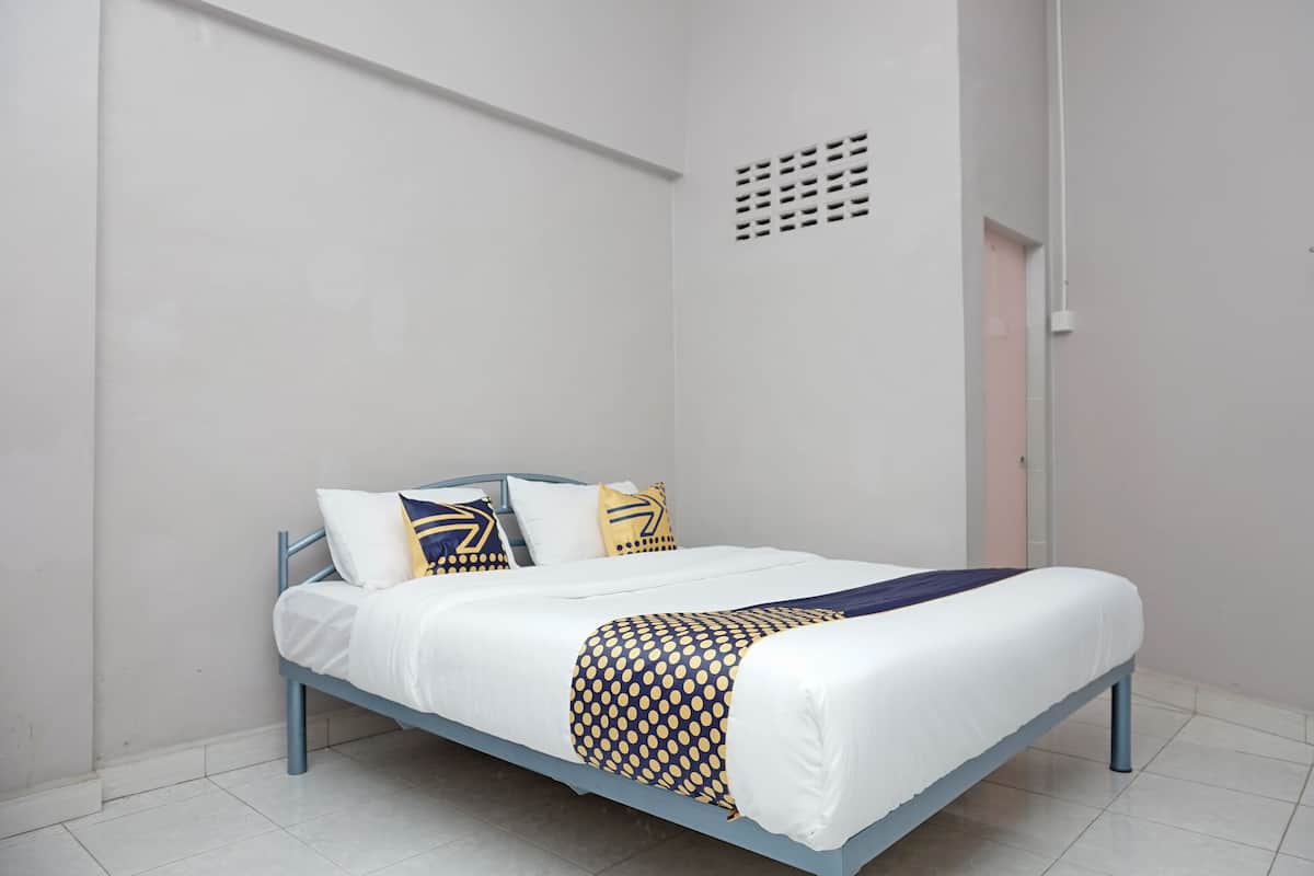 Ein Einzelbett mit blauem Metallgestell, weißer Bettwäsche und einer gemusterten Decke.