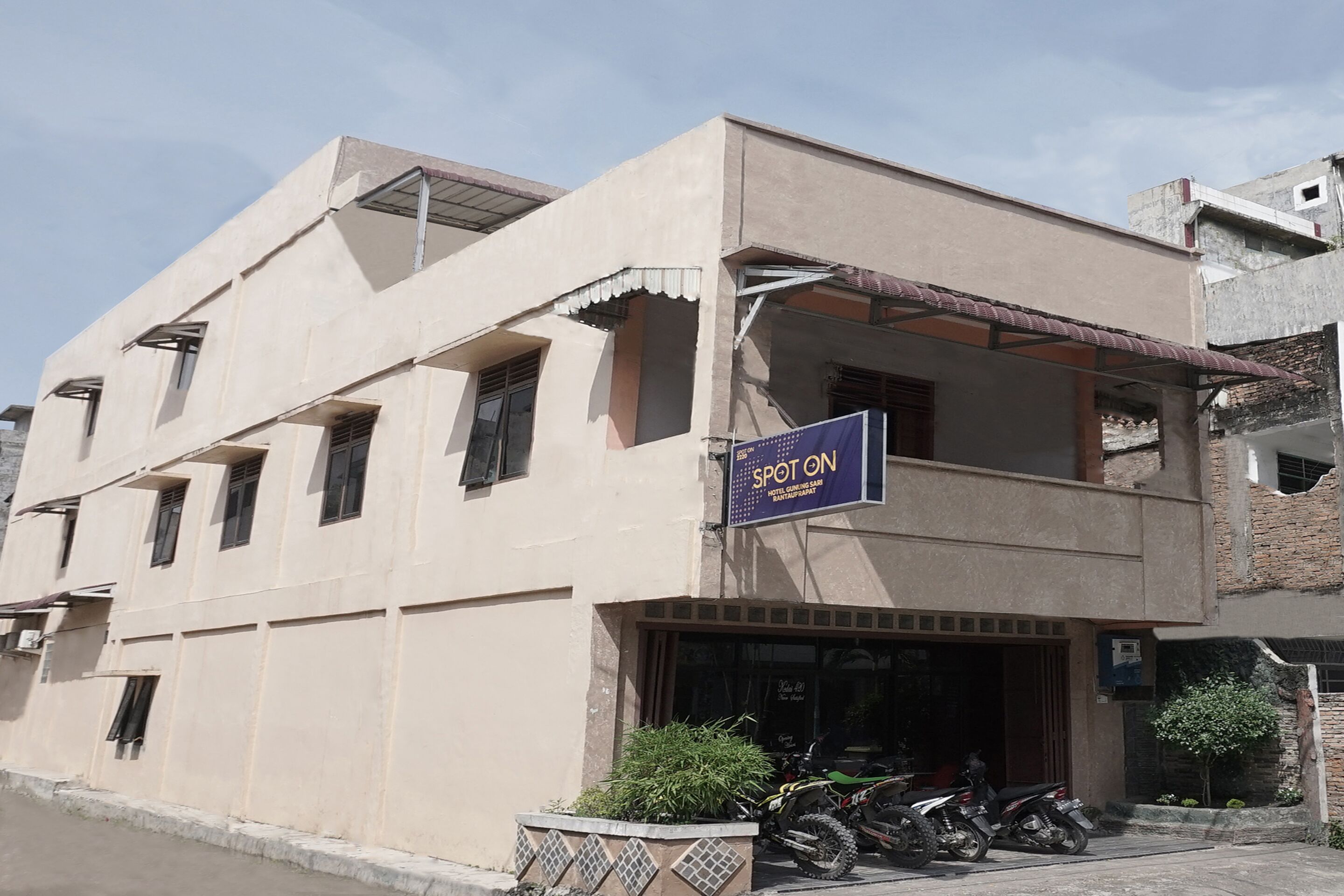 A building with a sign reading "SPOT ON" and a motorcycle parked in front.