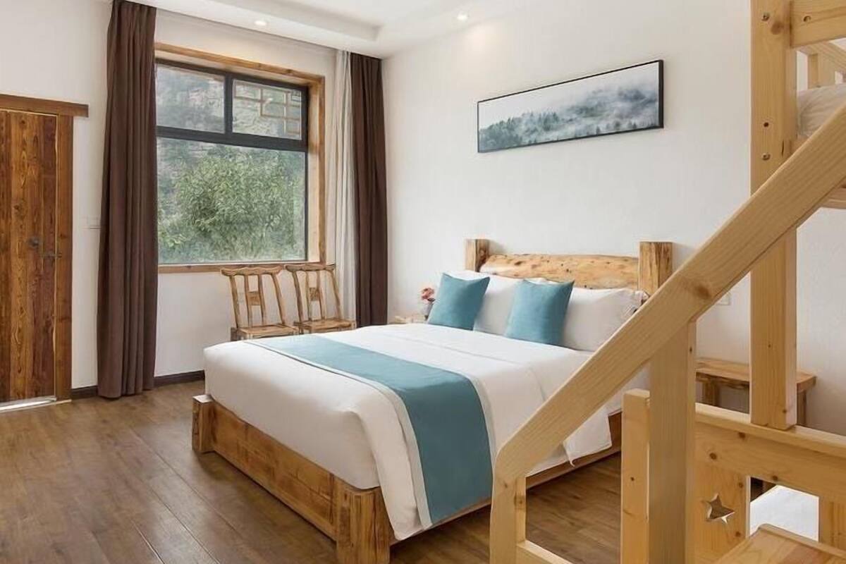 Quarto com cama de madeira, janela com cortinas, um quadro na parede e escada de madeira.