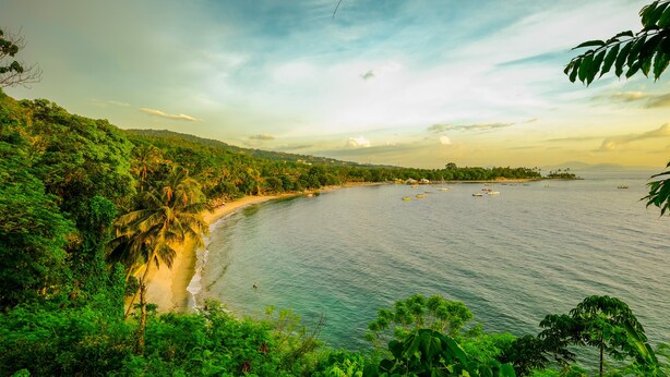A coastal landscape with a beach, dense greenery, and a clear sky. - OYO 2284 Grand Villa Meninting (Senggigi)