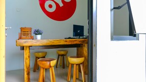 A wooden table with four stools, a potted plant, and a red circular sign with the word "OYO" on a wall. - OYO 2284 Grand Villa Meninting (Senggigi)