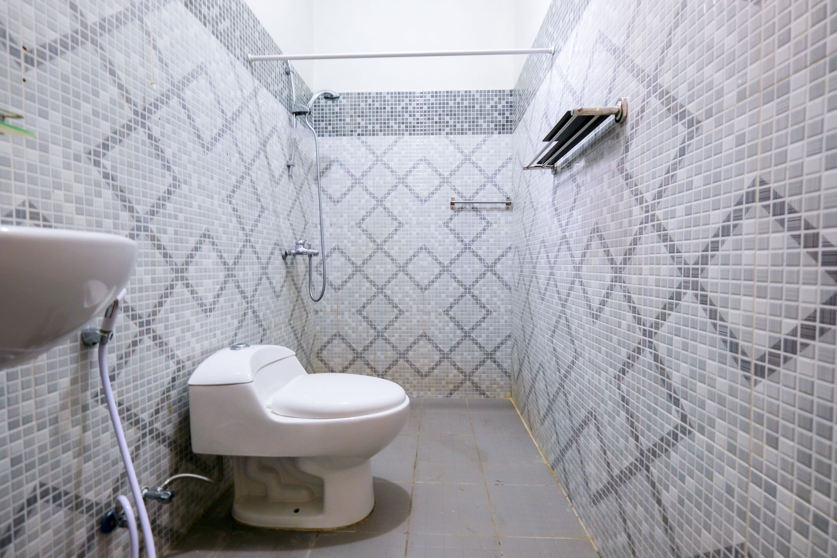 A small bathroom with a toilet, a sink, and a shower area.