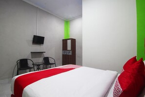 A hotel room with a bed, two chairs, a TV, and a wardrobe. - Hotel O isma Laut Tawar Syariah (Bandar Lampung)