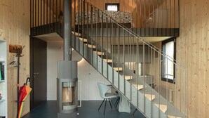 A modern interior with a wooden ceiling, a spiral staircase, a built-in bed, and a central glass fireplace. - Retreat in Malcantone (Alto Malcantone)