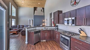Une cuisine moderne avec des meubles de couleur bois foncé, des appareils en acier inoxydable et un plafond en bois.