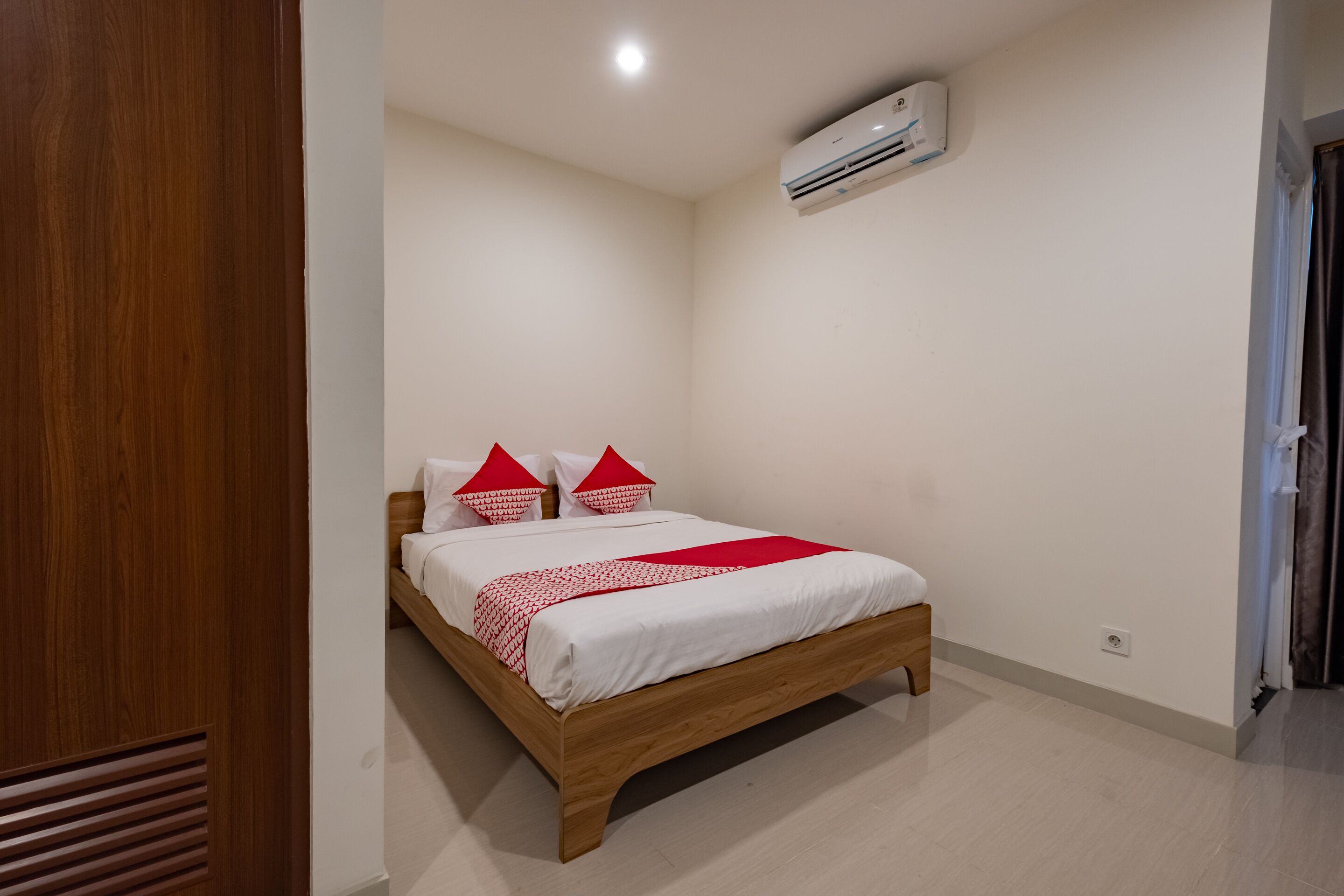 Une chambre à coucher avec un lit en bois, du linge de lit blanc et des oreillers rouges.