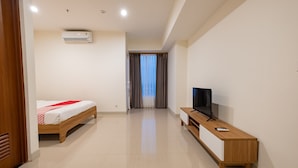 A hotel room with a bed, TV, and a wooden bench. - OYO 2245 Apartment Grand Kamala Lagoon (Bekasi)
