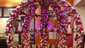 A room with a white fur-covered bed, a floral arch, and a small table with a decorative item. - Hotel Shivam (Kalyan)
