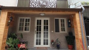 Un edificio de dos plantas con un balcón, entrada de madera y un letrero con el logotipo de un ave.