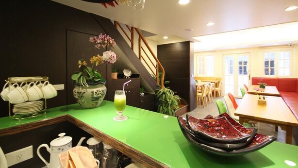 Una cocina moderna con encimera verde, una estación de café y una escalera que lleva a un comedor.