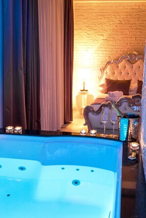 A luxurious bedroom with a large bathtub, a tufted headboard, and a brick wall. - SuiteFrattini (Rome)