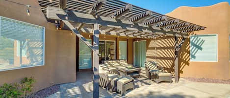 A covered outdoor seating area with wicker furniture and string lights.
