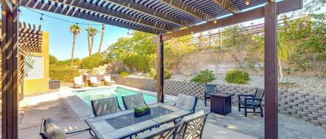 A covered outdoor area with a pool, seating, and a pergola with string lights.