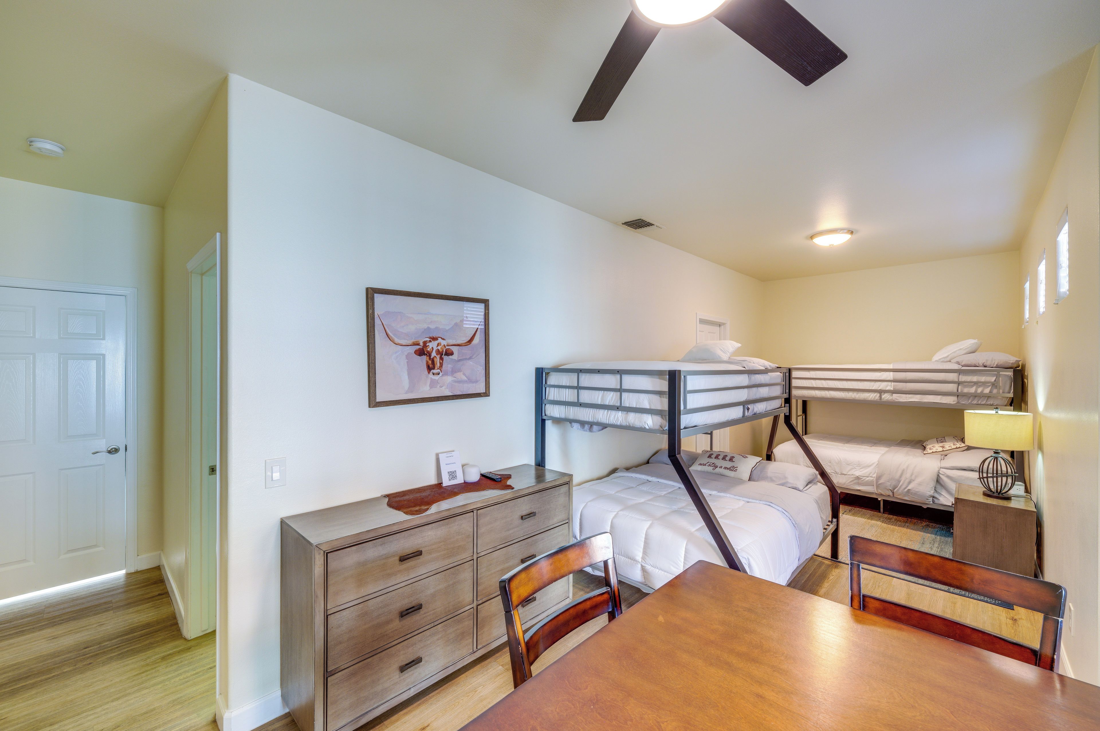 A compact room with bunk beds, a wooden dresser, a desk, and a chair.