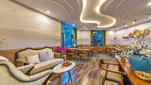 Un área de comedor moderna con sofá, mesa, sillas y una planta decorativa.