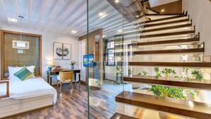 A modern hotel room with a wooden ceiling, a glass staircase, a bed with white linens, a desk with a computer, and a view of the outdoors. - Floral Hotel Yun Shui Snow Mountain (Lijiang)
