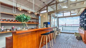 A bar area with wooden shelves, hanging pendant lights, and a view of the water outside. - Floral Hotel Yun Shui Snow Mountain (Lijiang)
