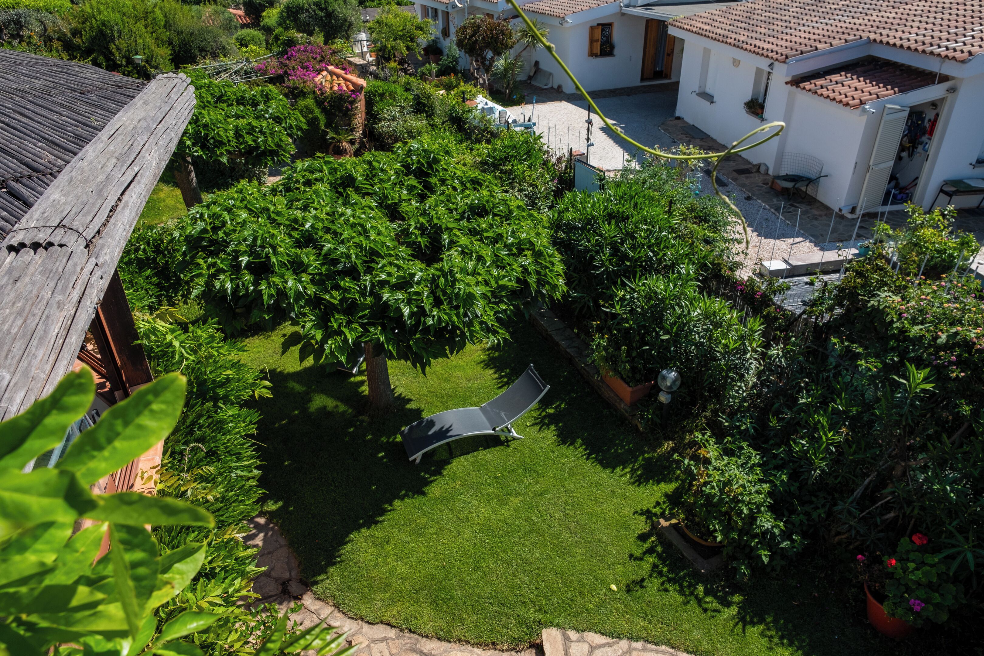 Un barrio residencial con un césped cuidado, una terraza de madera y una casa con tejado de tejas.