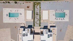 An aerial view of a hotel with two swimming pools, a central courtyard, and multiple rooms.